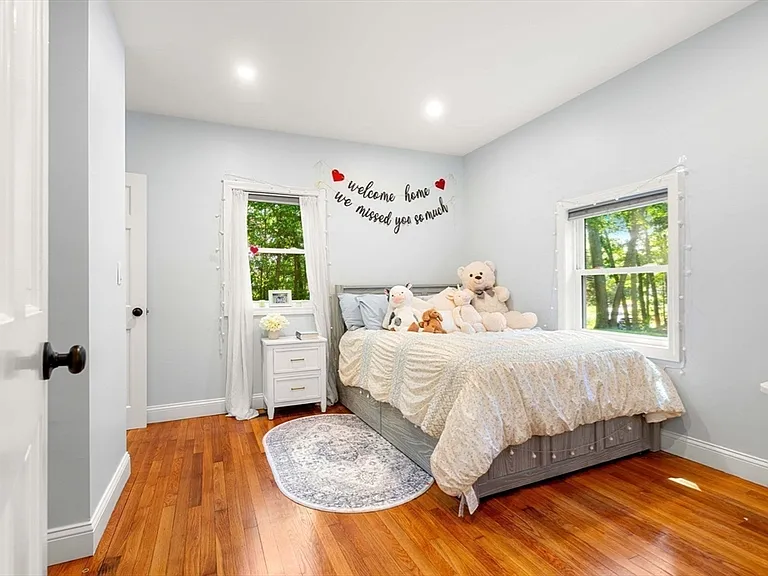 Light-filled guest bedroom with double windows and hardwood floors