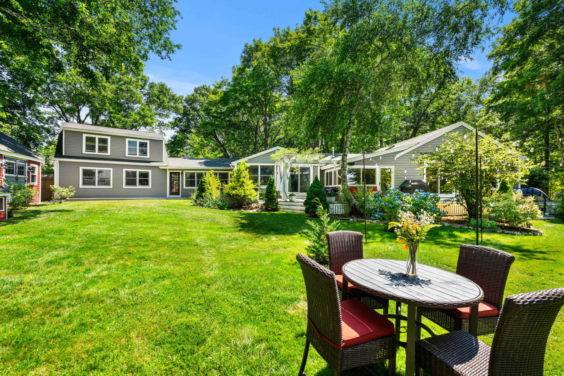 Rear elevation of the home with expansive lawn and gardens