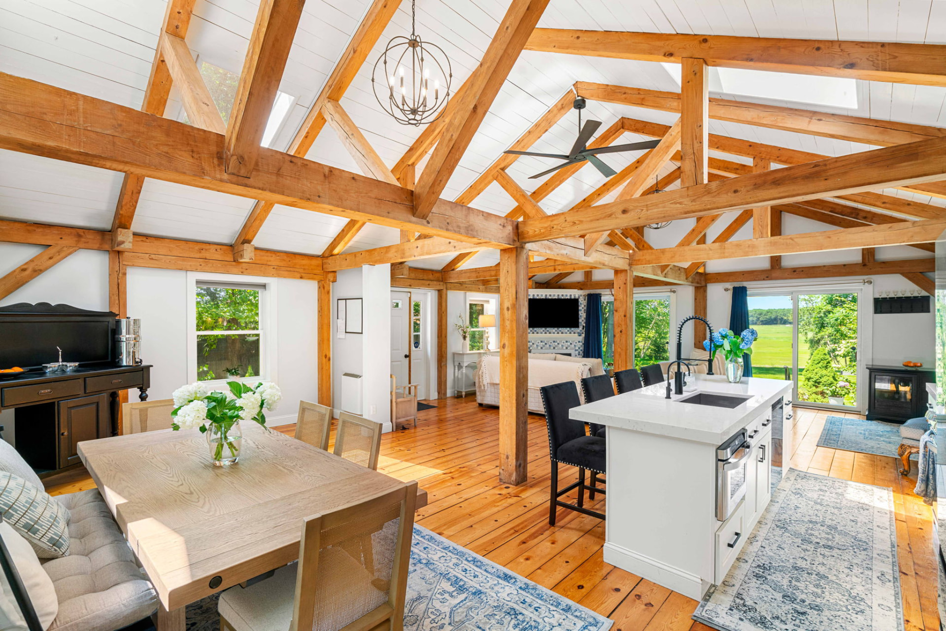 Open-concept great room with exposed timber trusses and pine floors